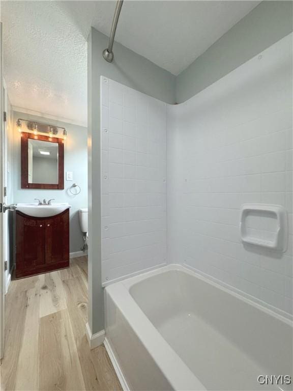 full bathroom featuring hardwood / wood-style floors, vanity, a textured ceiling, and washtub / shower combination