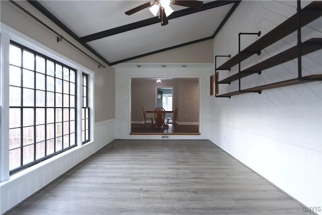 empty room featuring ceiling fan, plenty of natural light, lofted ceiling, and light hardwood / wood-style flooring