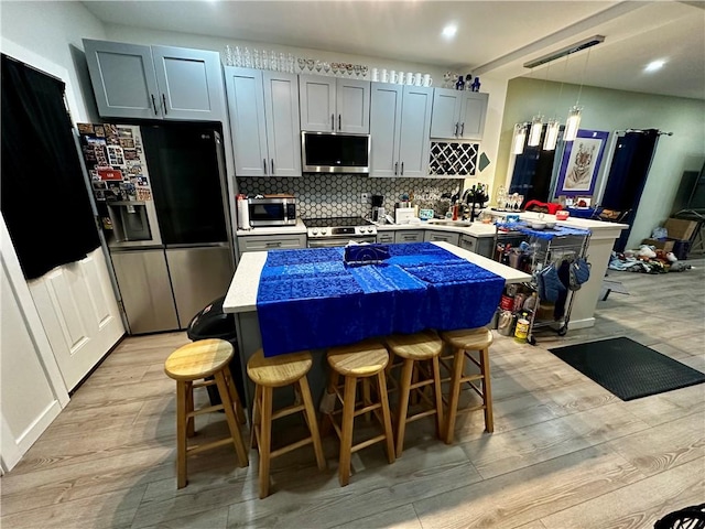 kitchen featuring pendant lighting, a center island, a kitchen bar, and appliances with stainless steel finishes