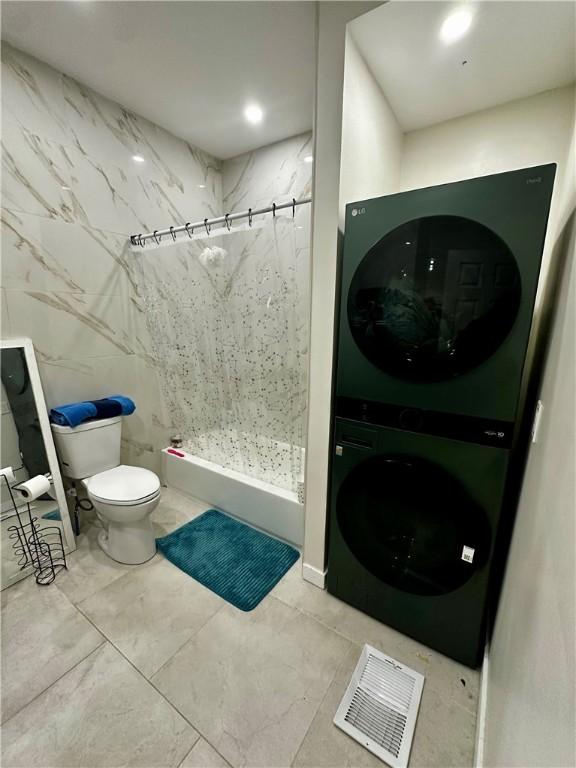 bathroom featuring curtained shower, toilet, and stacked washer / dryer