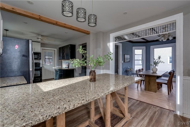 kitchen with ceiling fan, light stone counters, dark hardwood / wood-style flooring, stainless steel fridge, and decorative light fixtures