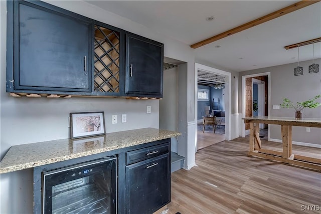 bar with beam ceiling, light stone countertops, beverage cooler, and light hardwood / wood-style floors