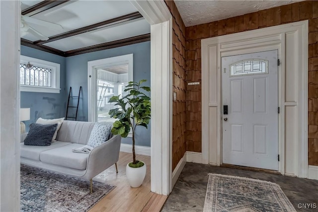 foyer entrance featuring a textured ceiling, crown molding, ceiling fan, and wooden walls