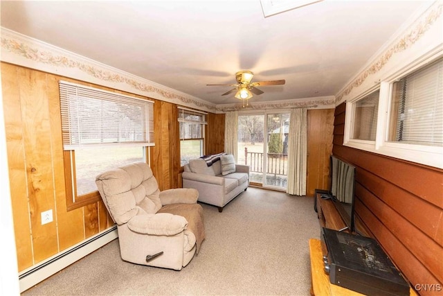 living area with carpet floors, crown molding, ceiling fan, and a baseboard heating unit