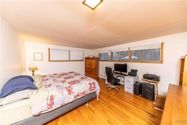 bedroom with hardwood / wood-style flooring and a baseboard heating unit