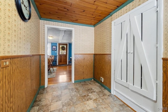 hall featuring crown molding, wooden walls, and wood ceiling