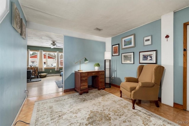 sitting room featuring a textured ceiling, ceiling fan, baseboard heating, and light parquet floors