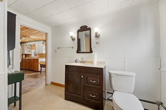 bathroom with vanity, toilet, ornamental molding, and a baseboard heating unit