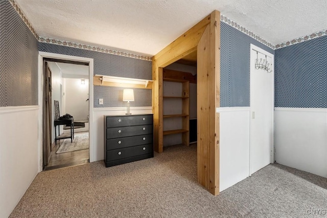 interior space with carpet, a textured ceiling, and wooden walls