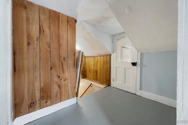 bonus room with lofted ceiling and wood walls