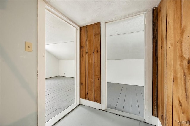 hall with wood walls and vaulted ceiling