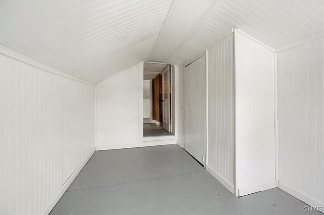 additional living space with wood walls, concrete floors, and vaulted ceiling