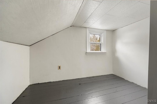 additional living space with hardwood / wood-style flooring and vaulted ceiling