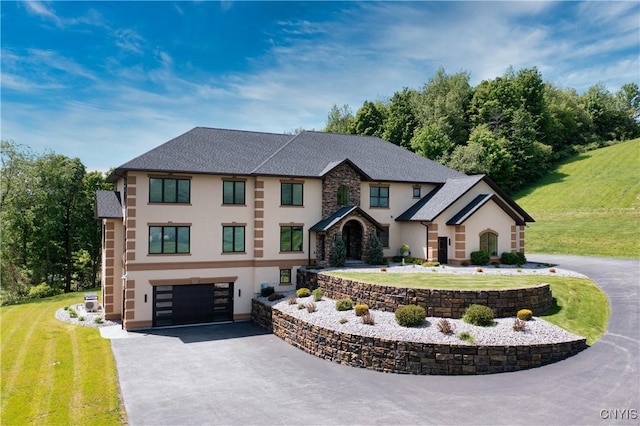 view of front facade with stucco siding, a front yard, a garage, stone siding, and driveway