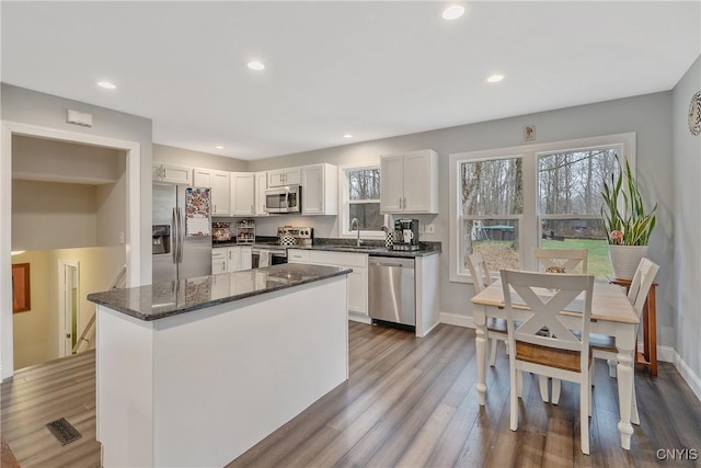 kitchen featuring dark stone countertops, dark hardwood / wood-style flooring, white cabinets, and appliances with stainless steel finishes