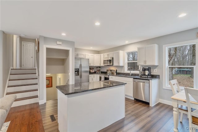 kitchen featuring white cabinetry, sink, stainless steel appliances, dark stone countertops, and a kitchen island