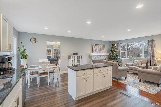 kitchen with dark stone counters, white cabinetry, dark wood-type flooring, and stainless steel dishwasher