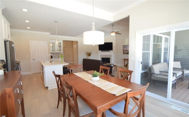 dining area featuring ceiling fan, light hardwood / wood-style floors, ornamental molding, and sink