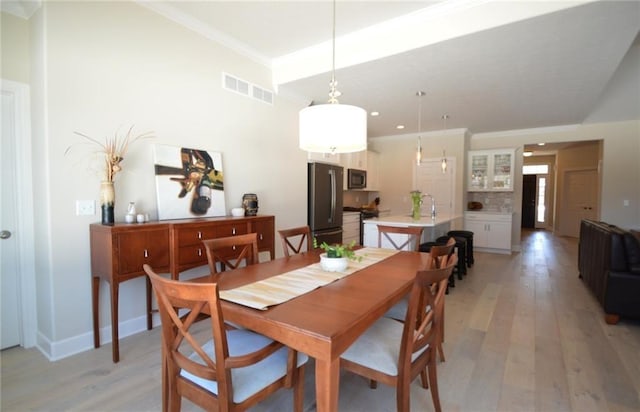 dining area with crown molding and light wood-type flooring