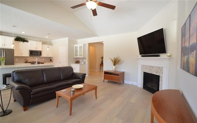 living room featuring vaulted ceiling, light hardwood / wood-style flooring, and ceiling fan