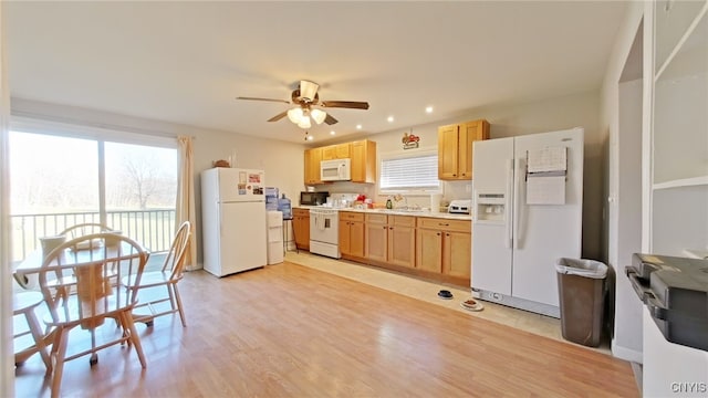 kitchen featuring white appliances, sink, ceiling fan, light wood-type flooring, and light brown cabinetry