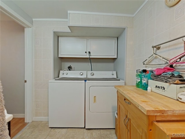 laundry area featuring washer and clothes dryer, cabinets, and tile walls