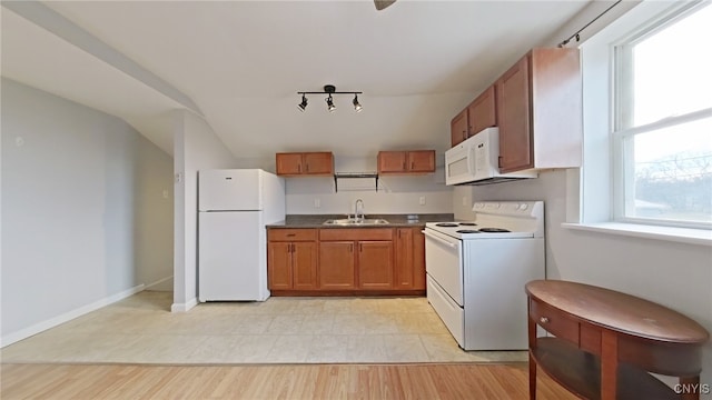 kitchen featuring white appliances, light hardwood / wood-style flooring, vaulted ceiling, and sink