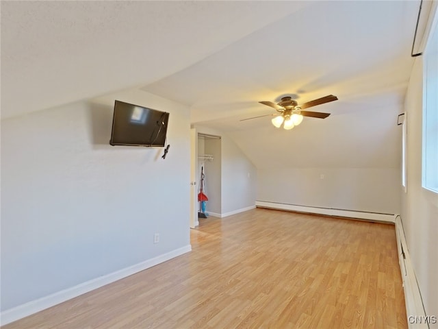 additional living space with ceiling fan, light wood-type flooring, vaulted ceiling, and a baseboard heating unit