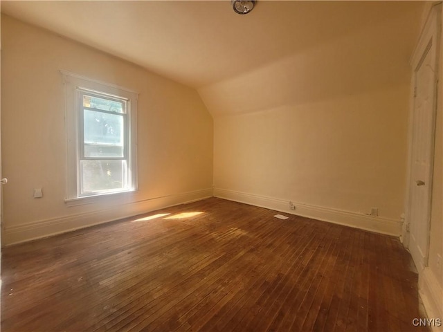 additional living space featuring dark wood-type flooring and lofted ceiling