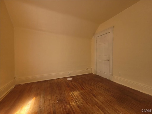 additional living space featuring dark wood-type flooring and vaulted ceiling