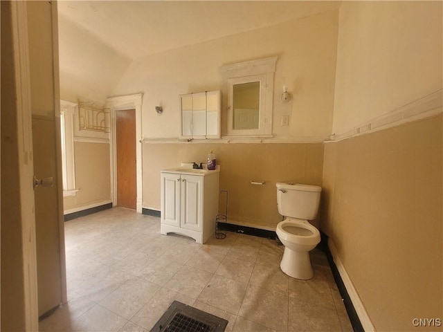 bathroom featuring tile patterned flooring, vanity, toilet, and lofted ceiling