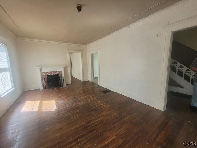 unfurnished living room with crown molding, dark wood-type flooring, and a tiled fireplace