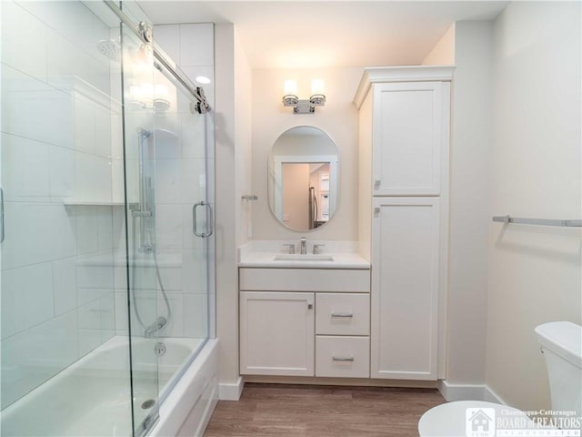 full bathroom with vanity, hardwood / wood-style flooring, combined bath / shower with glass door, and toilet