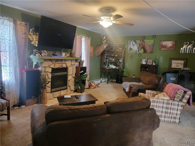 carpeted living room with a baseboard heating unit, a stone fireplace, ceiling fan, and plenty of natural light