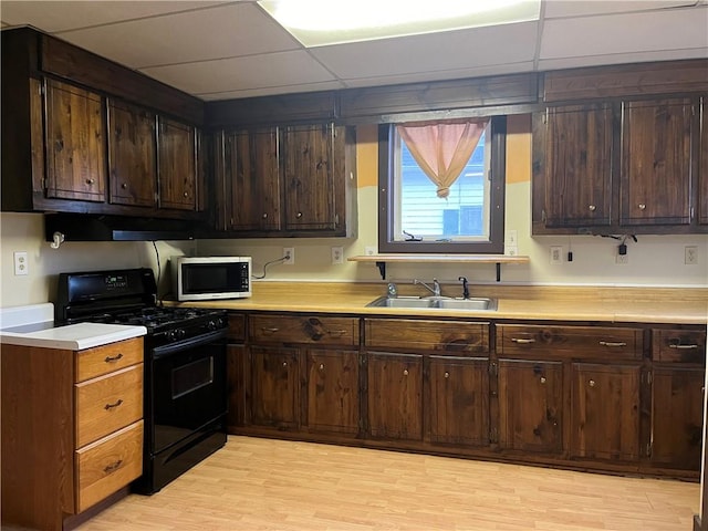 kitchen featuring black range with gas stovetop, dark brown cabinetry, sink, and a drop ceiling