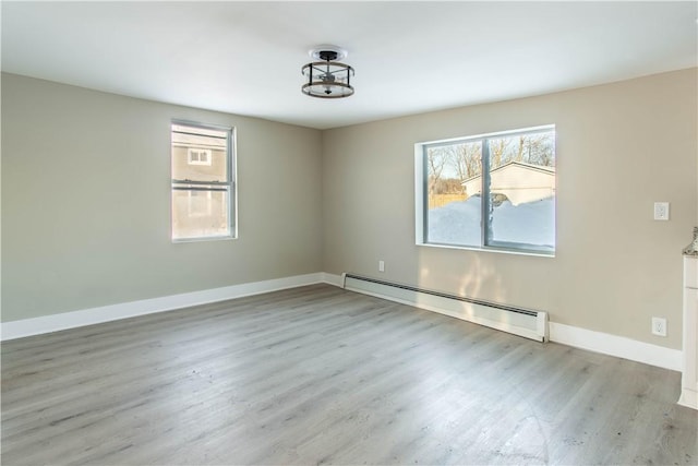 empty room with baseboard heating and light wood-type flooring