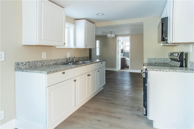 kitchen featuring electric stove, white cabinetry, light hardwood / wood-style floors, and sink