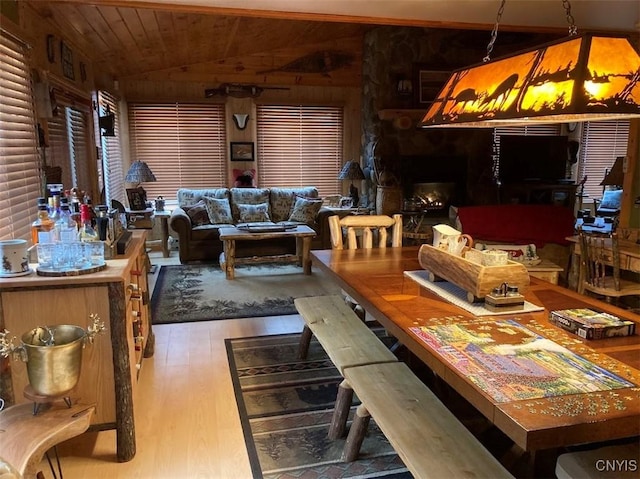 dining space featuring hardwood / wood-style floors, wooden ceiling, wooden walls, and vaulted ceiling