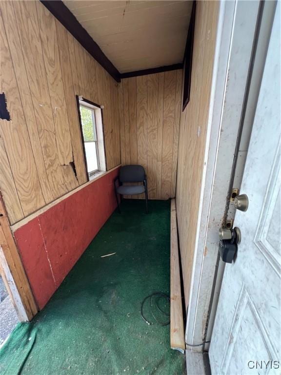 corridor featuring dark carpet and wood walls