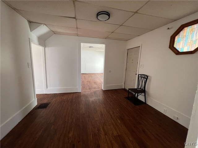 empty room with a paneled ceiling and dark wood-type flooring