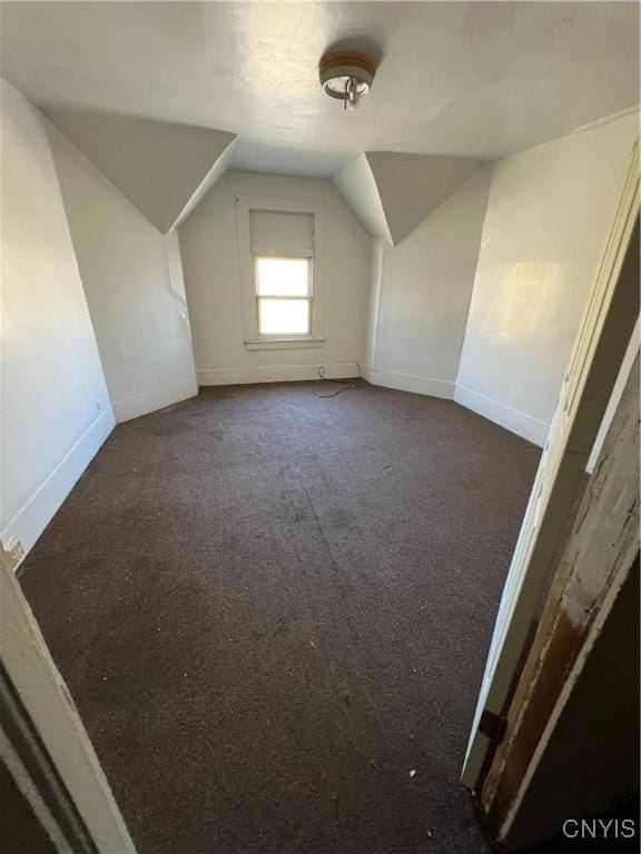 bonus room with dark carpet and vaulted ceiling