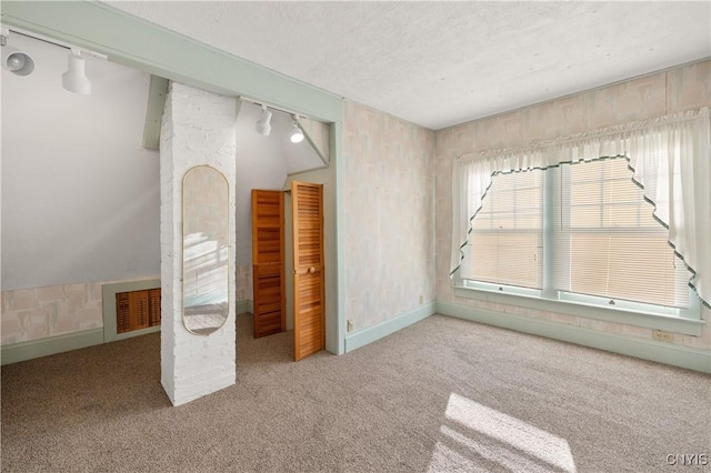 unfurnished bedroom featuring light colored carpet, track lighting, and lofted ceiling