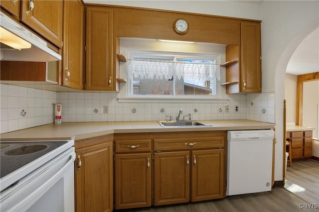 kitchen featuring backsplash, white appliances, sink, and hardwood / wood-style floors