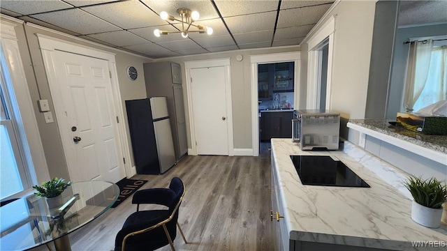 kitchen featuring light stone counters, sink, hardwood / wood-style flooring, a notable chandelier, and stainless steel refrigerator