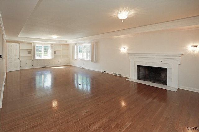 unfurnished living room featuring a raised ceiling and dark wood-type flooring