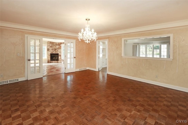 spare room with dark parquet flooring, french doors, a fireplace, ornamental molding, and a notable chandelier