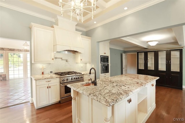 kitchen featuring light stone countertops, appliances with stainless steel finishes, white cabinetry, a kitchen island with sink, and sink