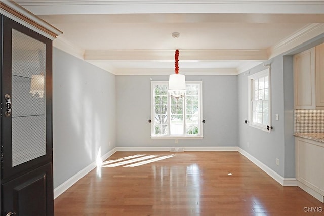 unfurnished dining area featuring light hardwood / wood-style floors, crown molding, and beamed ceiling