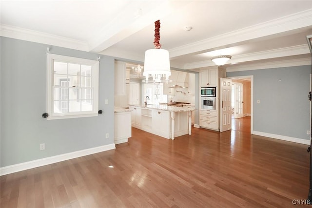 kitchen with custom exhaust hood, appliances with stainless steel finishes, a kitchen breakfast bar, pendant lighting, and an island with sink