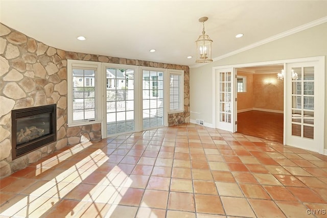 unfurnished living room with a stone fireplace, french doors, ornamental molding, vaulted ceiling, and light tile patterned floors